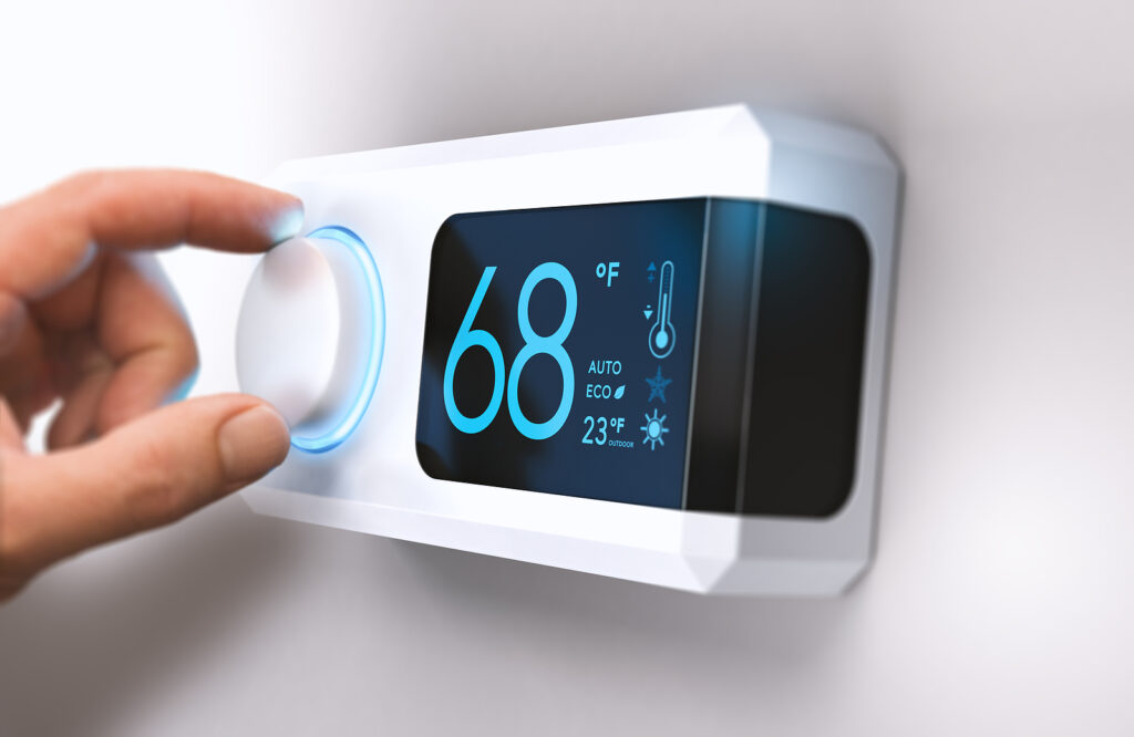 Person's hand setting digital thermostat.